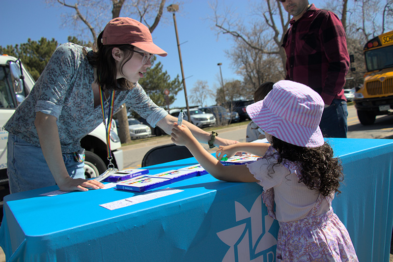 A library staff worker shows a table display to a child while outside at an outreach event. 