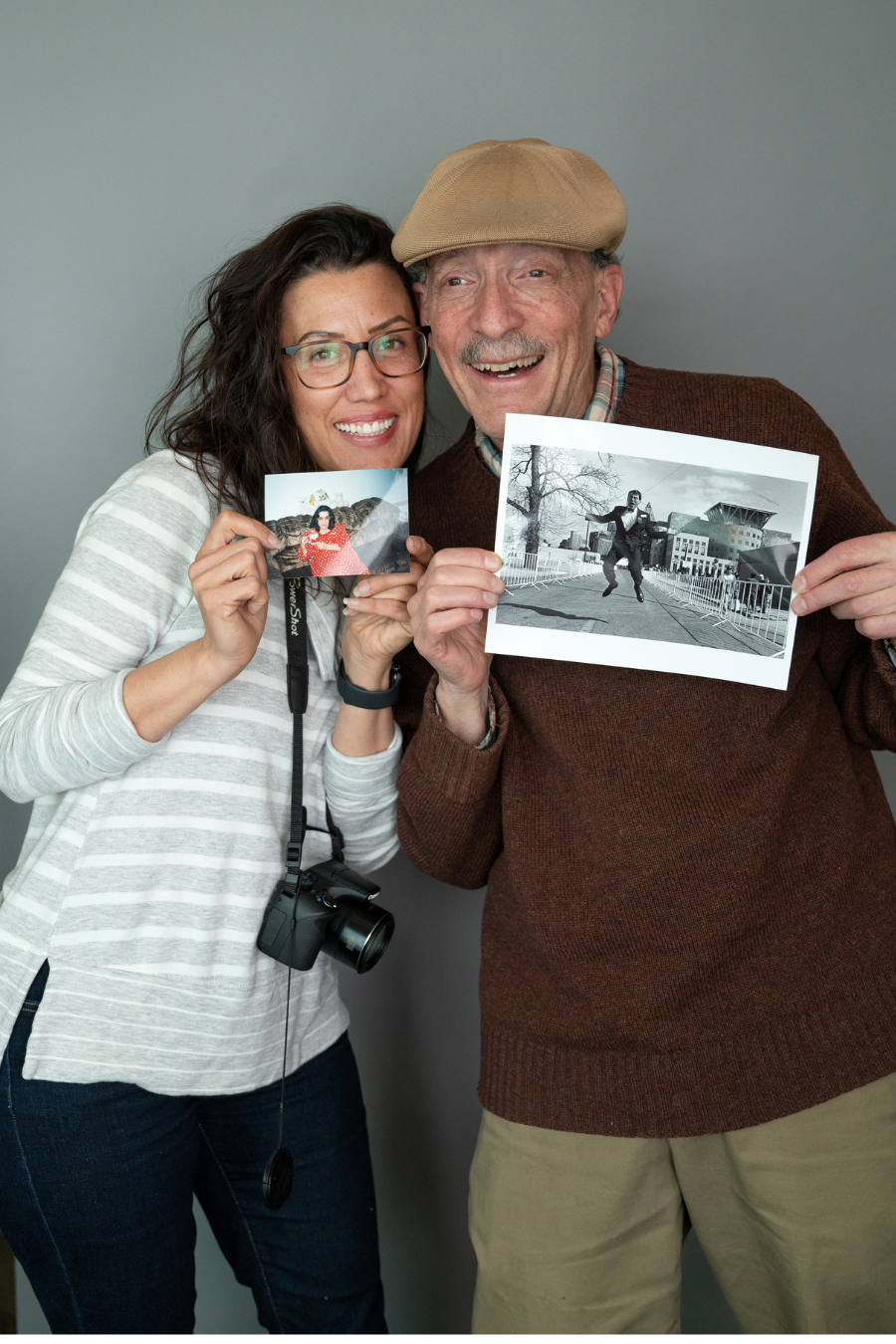 Young woman and older male adult holding up photographs